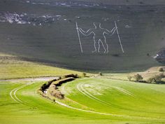 two people standing in the middle of a green field with white lines drawn on them