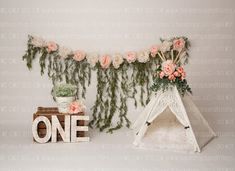 a teepee with flowers on it next to a sign that says one in white