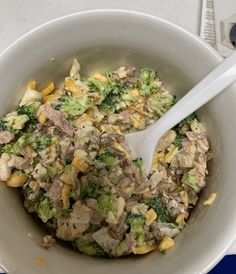 a white bowl filled with broccoli and other food on top of a table