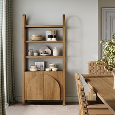 a wooden shelf with dishes on it next to a window