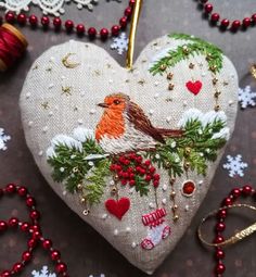 an ornament shaped like a heart with a bird on it, surrounded by christmas decorations