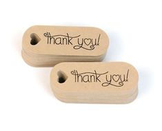 two wooden tags with the words thank you written in black ink on them, sitting next to each other