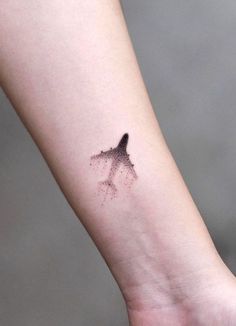 a small tattoo on the wrist of a person's arm with a bird flying in the sky