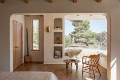 a bedroom with a bed, chair and window looking out onto the outdoors in front of it