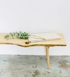 a wooden table topped with green plants and a white sheet of paper on top of it