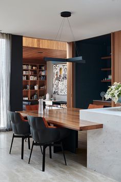 the dining room table is surrounded by black chairs and wooden bookshelves, along with a large painting on the wall