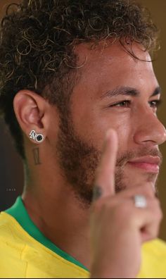 a close up of a person giving the peace sign with his hand and wearing earrings