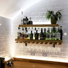 there are many bottles and glasses on the shelves in this room with white brick walls