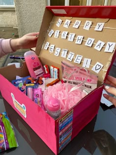 a pink box filled with personal care items and birthday wishes written on the side, sitting on top of a table