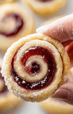 a hand holding a pastry with jelly inside