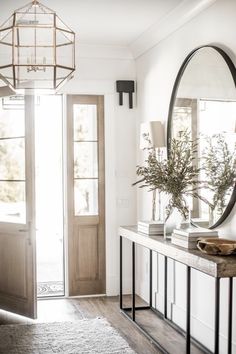 a mirror sitting on top of a white table next to a doorway with a plant in it