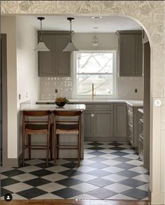 a kitchen with checkered flooring and two chairs at the table in front of an archway