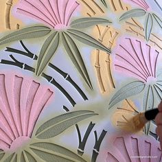 someone is using a brush to paint the design on a piece of paper with pink and green leaves