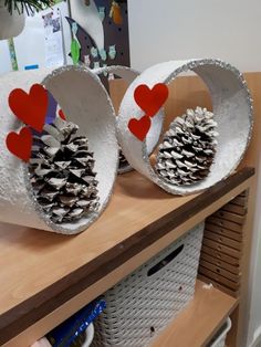 two pine cones with hearts on them are sitting on a shelf in front of a christmas tree