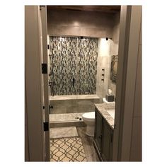 an open door leading to a bathroom with tile flooring and wallpaper on the walls