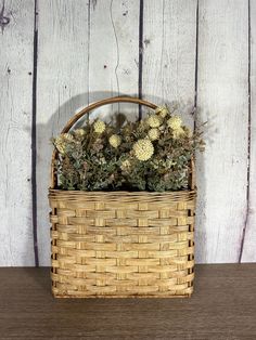 a basket filled with flowers sitting on top of a wooden table next to a wall