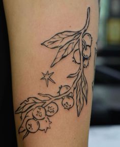 a tattoo on the leg of a woman with berries and leaves around her arm,