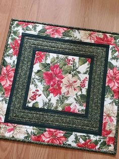 a close up of a flowered placemat on a wooden floor with a black border