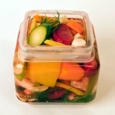 two plastic containers filled with assorted veggies on top of a white surface