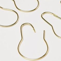 four pairs of gold - plated metal hooks on a white surface, with one hook in the middle