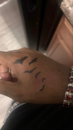 a person's arm with birds on it and a red beaded bracelet around the wrist