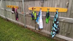 several surfboards are hanging on the side of a fence with towel racks attached to it