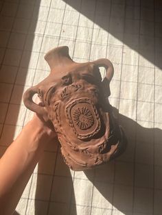 someone is holding a clay vase in their hand