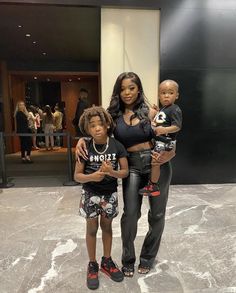 a woman standing next to two children in front of a building