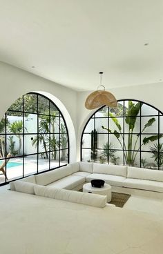 a large white couch sitting in front of two arched windows next to a swimming pool