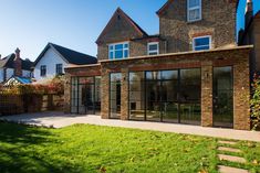 a brick building with glass doors and windows on the outside, in front of a green lawn