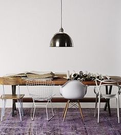 a dining room table with chairs and a lamp hanging over it's head, in front of a white wall