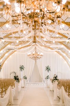 an indoor wedding venue with chandeliers and white drapes