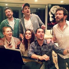 a group of people standing in front of a laptop computer with one man holding his arm out