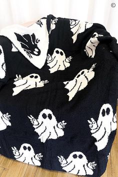 a black and white blanket with ghost faces on it sitting on a wooden floor in front of a window