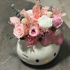 a hello kitty vase filled with pink and white flowers