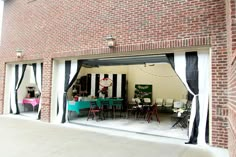 an open garage door with black and white striped curtains on the outside, showing tables and chairs