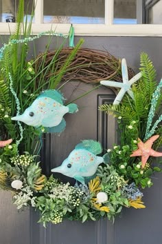 a wreath with two fish and plants on the front door