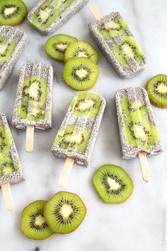 kiwi popsicles are sitting on a table with slices of kiwi in them