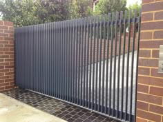 an iron gate with brick wall and driveway