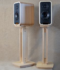 two wooden speakers are standing on stands