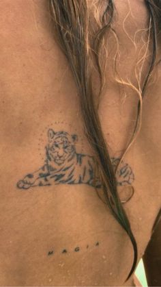 a man with long hair has a tiger tattoo on his chest