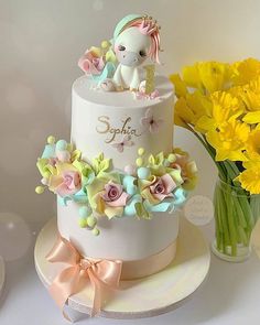 there is a white cake with flowers and a unicorn figurine on the top