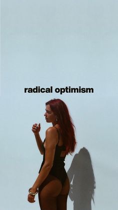 a woman in a bathing suit standing next to a wall with the words radical optimism on it