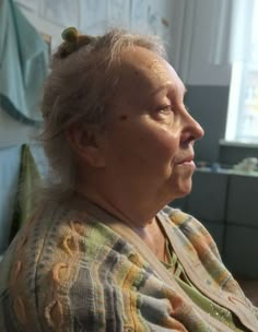 an older woman sitting in a chair looking off into the distance with her eyes closed