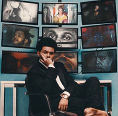 a man sitting on top of a chair in front of a wall covered with pictures