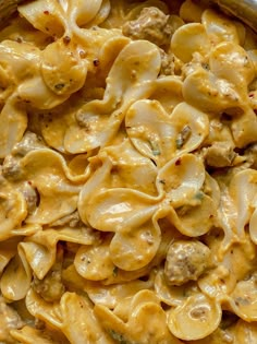 a pan filled with pasta and meat covered in cheese sauce on top of a wooden table