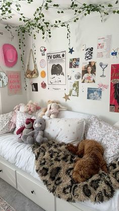 a bed with pillows and stuffed animals on top of it in a room decorated with posters