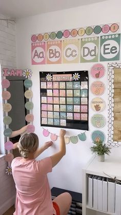 a woman sitting in front of a chalkboard with magnets on it and writing