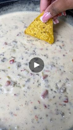 a person dipping a tortilla chip into a bowl of white quesadilla soup