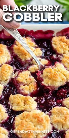 blackberry cobbler in a white baking dish with a serving spoon